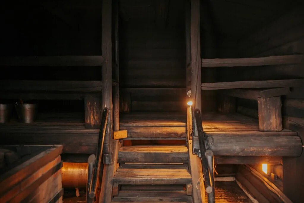 the soot-darkened log benches of the kuurakaltio smoke sauna, lit by small lamps