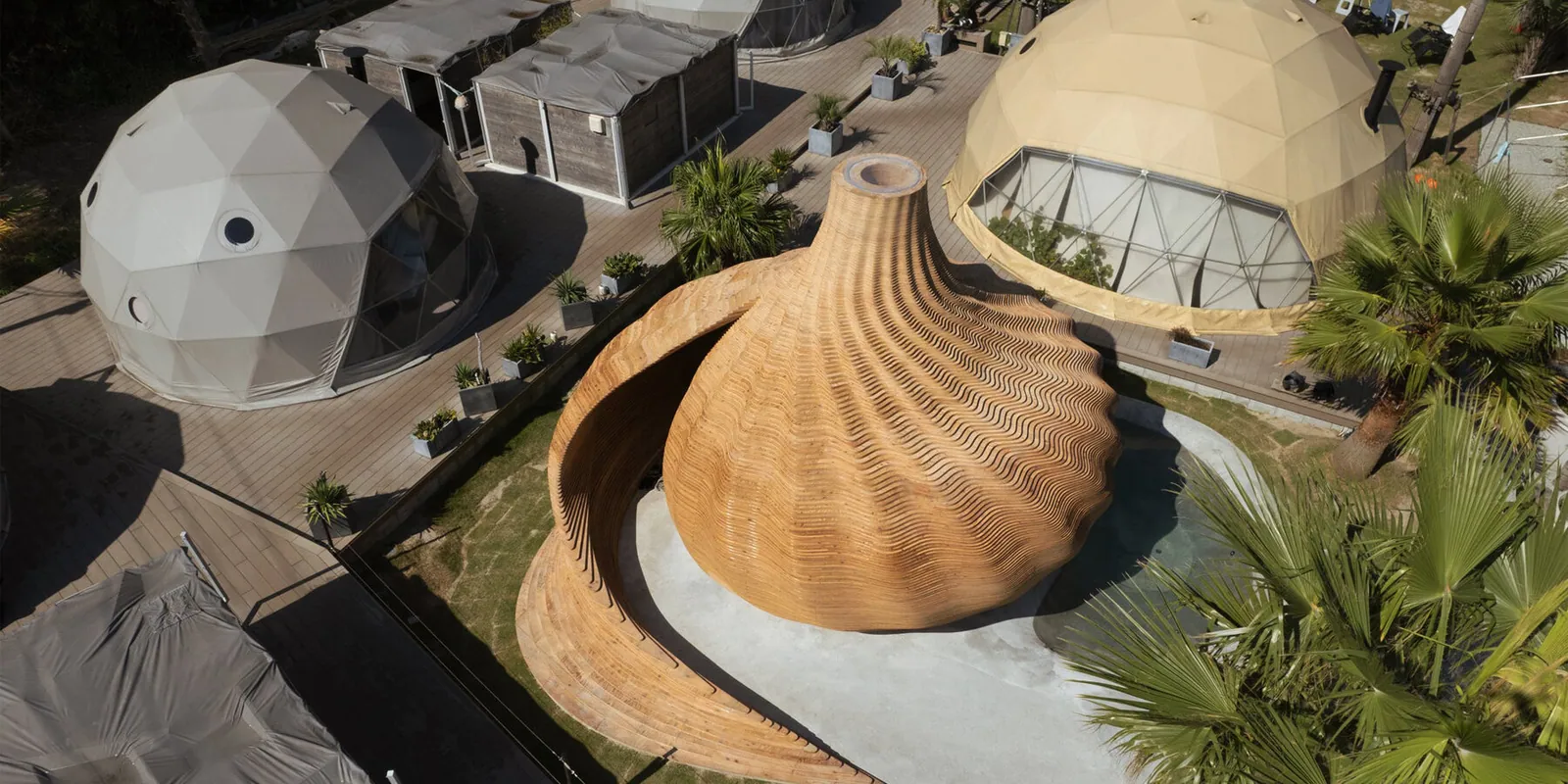 aerial view of the spiral seashell-shaped wooden sauna among glamping domes
