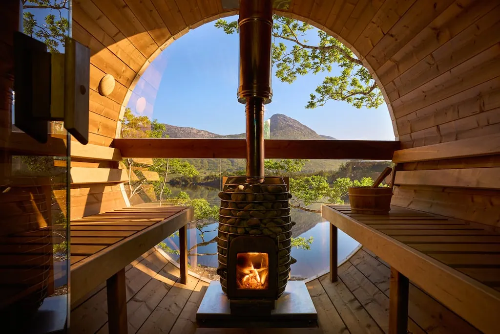 a wood-burning stove between two benches, a glass end framing a lake and a connemara peak